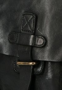 Fermaglio in pelle nera con una cinghia cucita e una fibbia metallica. Superficie testurizzata con una leggera lucentezza e accenti di design minimalista.