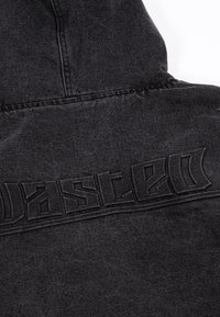 Juodas džinsinis džemperis su tekstūruotu "DASCED" logotipu ant nugaros, išsiskiriantis lygia apdaila ir struktūrine kapišonu.