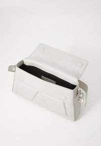 Sac à main rectangulaire en cuir blanc avec rabat ouvert, deux poches avant, doublure intérieure noire et fermoir en métal argenté sur la lanière latérale.