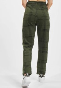 Grøn rutete joggebukser med en myk tekstur, med elastisk midjebånd og svart striper. Kombinert med hvite joggesko.