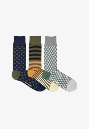 Drei Paar Socken: marineblau mit Punkten, oliv- und orangegestreift, grau mit geometrischem Muster. Baumwollmischung, gerippte Bündchen, DillySocks-Branding.
