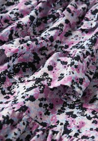 Tessuto a motivo floreale con sfumature di rosa, blu e nero. La texture è morbida, con accentuazioni arruffate e un design fluido.
