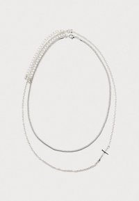 Δύο ασημένια κολιέ, το ένα με ένα μικρό οριζόντιο σταυρό ως κρεμαστό περιδέραιο, και τα δύο τοποθετημένα επίπεδα σε λευκό φόντο.