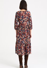 Robe imprimée florale avec manches trois-quarts, design à volants, présentant des couleurs rouge, bleu et crème, confectionnée en tissu doux.