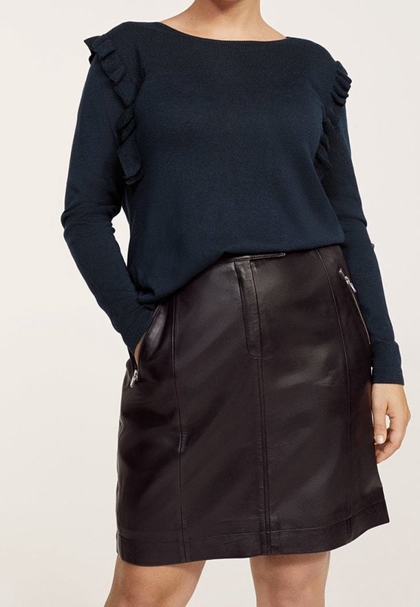 Námořnický modrý svetr s volánkovým detailem na ramenech, kombinovaný s černou koženou mini sukni s bočními kapsami a zipy. Hladké textury.
