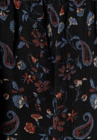 Černá tkanina s květinovým a paisley vzorem v červené, modré a krémové barvě. Textura se zdá být hladká s jemnými detaily.