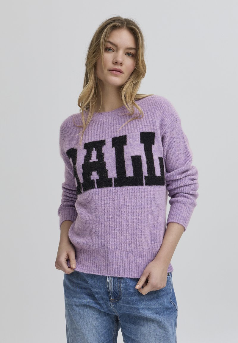 Lilla sviiter pehmest kangast, millele on mustade plokk-kirjadega kirjutatud "BALL". Sellel on ümar kaelus ning ribavarrukad ja alläär.