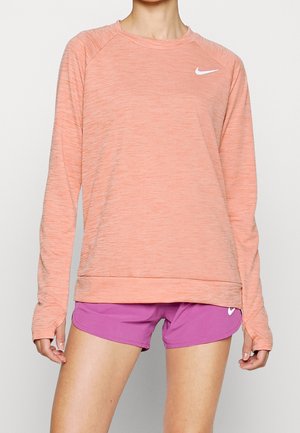 Licht koraal kleur lange mouwen sporttop met ribbeltextuur en ronde hals, gecombineerd met effen paarse shorts met een klein wit logo.