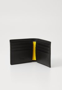 Carteira de couro preta com múltiplos compartimentos para cartões, apresentando um forro interior amarelo. Inclui detalhe do logótipo em relevê. Vista aberta.
