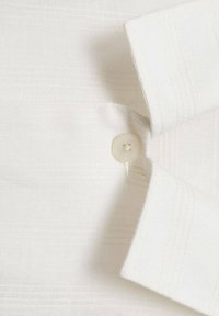 White shirt with a textured fabric featuring subtle vertical stripes. A round button is visible near the collar area.