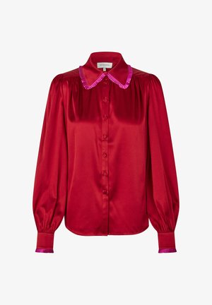 Blusa di raso rosso con colletto e polsini arricciati rosa, chiusura frontale con bottoni e maniche lunghe a sbuffo. Tessuto liscio con una finitura lucida.