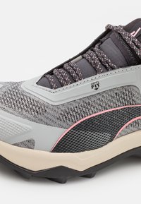 Szare buty sportowe z teksturowanym wierzchem, różowymi akcentami oraz solidną gumową podeszwą z wypustkami trakcyjnymi. Widoczne logo Opti-Fit.