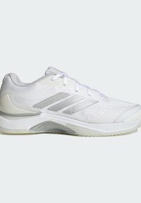 Biały but sportowy z oddychającą siateczkową cholewką, srebrnymi paskami ozdobnymi, gumową podeszwą oraz teksturowaną wyściółką zapewniającą przyczepność i wsparcie.