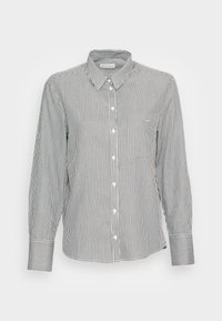 Chemise boutonnée présentant des rayures verticales noires et blanches, un col, une poche poitrine unique et des manches longues avec des poignets contrastants.
