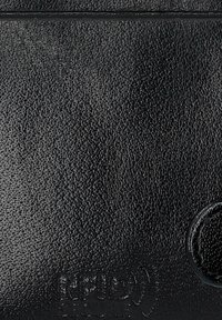 Czarny skórzany portfel o fakturowanej powierzchni, z wytłoczonymi detalami logo i okrągłym akcentem z metalowego dodatku.