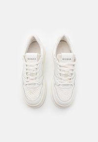 Baskets en cuir blanc avec un design texturé sur l'avant, fermeture à lacets et logo "GUESS" sur la languette. Bout arrondi et semelle épaisse.