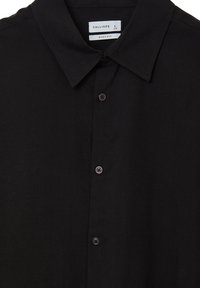 Camicia nera con colletto a punta, tre bottoni visibili e un'etichetta che recita "Calliope, Grande, Vestibilità Ampia."