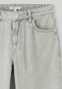 Jean ballon gris clair en tissu mélangé de coton. Comprend une poche avant, une fermeture à bouton métallique et des passants de ceinture.