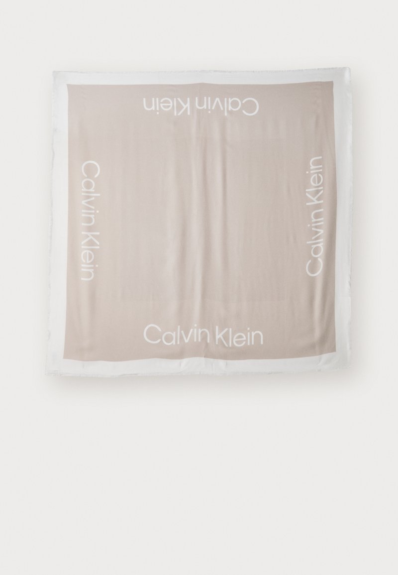 Calvin Klein skjerf i myk beige tekstil, med hvit logo tekst i hjørnene. Firkantet form med lett flising langs kantene.