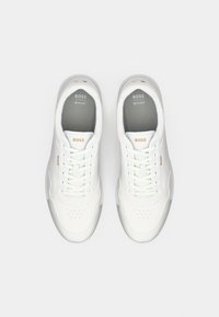 Adidași albi cu un superior din piele netedă, detalii perforate și accente bleu deschis. Prezintă închidere cu șireturi și căptușeală interioară moale.