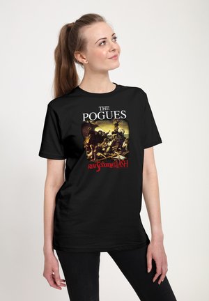 Ung kvinde med hestehale iført en sort t-shirt med The Pogues-bandets design og kunstværk fra albumcoveret "Rum Sodomy and the Lash".