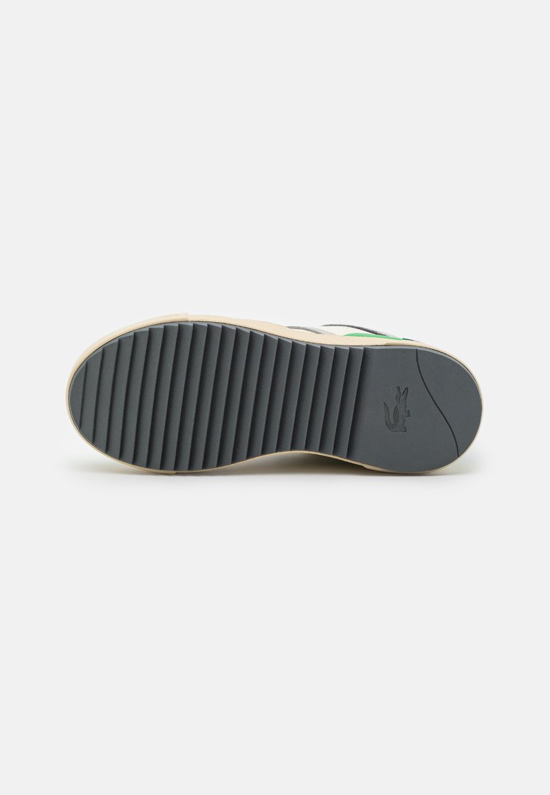Semelle de chaussure en caoutchouc avec texture striée. Caractérisée par des couleurs noire et beige clair, avec un emblème intégré au talon et un design plat.