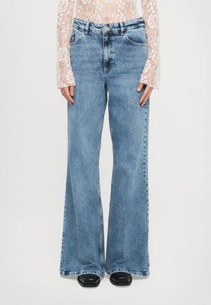 Light blue denim flared jeans with a mid-rise waist, five-pocket design, and raw hem detail at the cuffs. Features a faded texture.