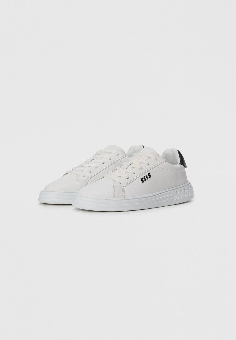 Baskets basses blanches avec lacets, onglet de talon noir et logo "MSGM" sur le côté et la semelle, présentées sur un fond blanc uni.