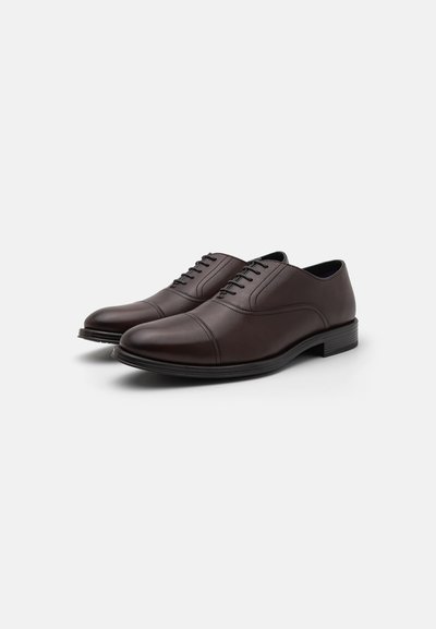 Scarpe da uomo in pelle marrone con punta arrotondata, design con lacci e una finitura liscia. Presentano un tacco basso impilato e dettagli di cucitura discreti.