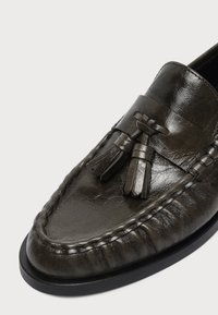 Σκούρο καφέ δερμάτινο loafer με φούντες και λεπτομερείς ραφές σε μαύρη σόλα, εμφανίζεται από επάνω-πλευρική γωνία.