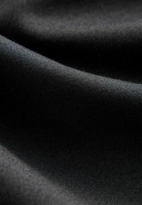 Tissu noir avec une texture lisse, présentant un léger éclat. Le matériau est étroitement tissé, mettant en avant une surface propre et uniforme.