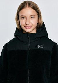 Mustan kapuutsiga jakk fuuri tekstuuriga, tõmbluku sulgemisega ja "Big Star Jeans" logo rinnal. Pehme kangas, millel on soe välimus.