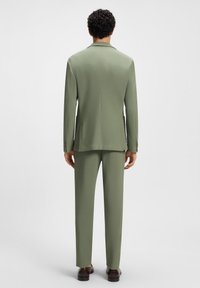 Groen colbert met bijpassende rechte pantalon. Gemaakt van lichtgewicht stof met een gladde textuur en minimaal detail.