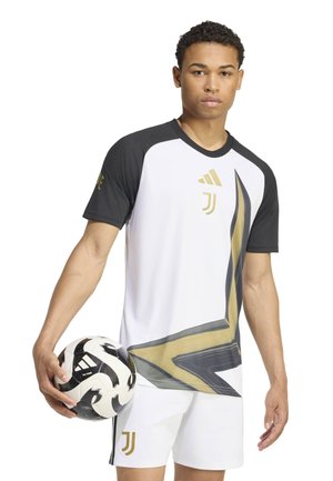 Junger Mann trägt ein weißes und schwarzes Juventus-Fußballtrikot mit goldenen Akzenten und hält in einer Hand einen schwarz-weißen Adidas-Fußball.