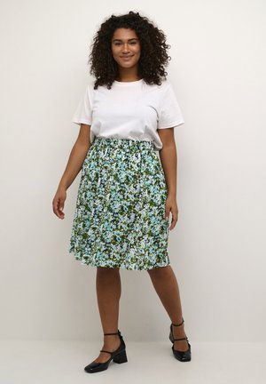 Blomstret nederdel i blå, grøn og hvid med en samlet talje. Kombineret med en enkel hvid t-shirt og sorte blokhæl sko.