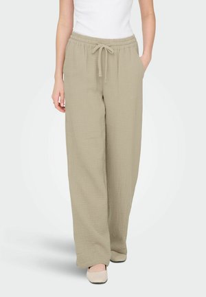 Pantaloni bej, cu picior larg, realizați dintr-un material texturat, având talie elastică și șnur reglabil. Se observă două buzunare laterale.