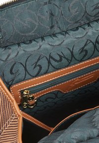 Borsa in tessuto marrone con un design a strisce testurizzato, caratterizzata da un interno teal con un sottile motivo a logo e una tasca con zip dorata.