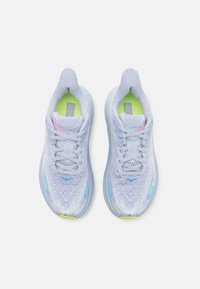 Scarpe da corsa azzurro chiaro con tomaia in mesh testurizzato, collare imbottito, suola bianca e dettagli verdi sulla soletta e sul logo. Inclusi lacci ed elementi di design.