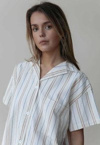 Kurzärmliges Hemd mit Knopfleiste aus leichtem Stoff mit vertikalen Streifen in Blau und Beige. Es verfügt über einen Notchkragen und eine Brusttasche.