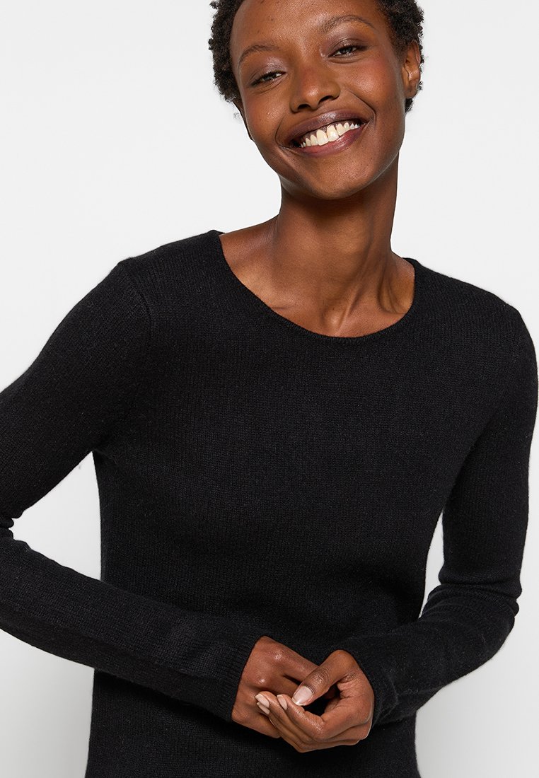 Schwarzer Langarmpullover aus strukturiertem Strickmaterial mit einem runden Halsausschnitt und engen Ärmeln, der ein schlichtes, klassisches Design zeigt.