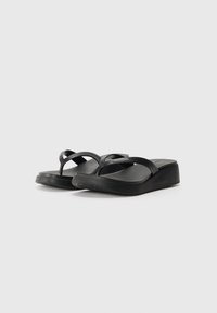 Sorte flip-flops med en teksturert gummisåle, kryssremdesign og en lett kilehælt. Glatt overflate med minimale merkevaredetaljer.