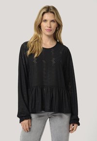 Black long-sleeve blouse with lace detailing, featuring a peplum waist and ruffled cuffs. Made of lightweight, textured fabric.