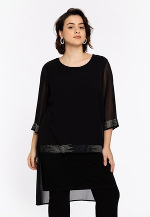 Tunique noire à manches transparentes 3/4 et ourlet orné de paillettes. Tissu doux avec un ajustement décontracté et un col rond.