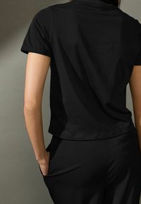 Sort kortærmet t-shirt med rund halsudskæring, lavet af blødt stof. Har en afslappet pasform og en let cropped længde.