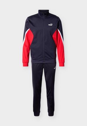 Marineblauer Puma-Trainingsanzug mit roten und weißen Akzenten an den Ärmeln, Reißverschlussjacke und passenden Hosen, auf einfarbigem Hintergrund dargestellt.