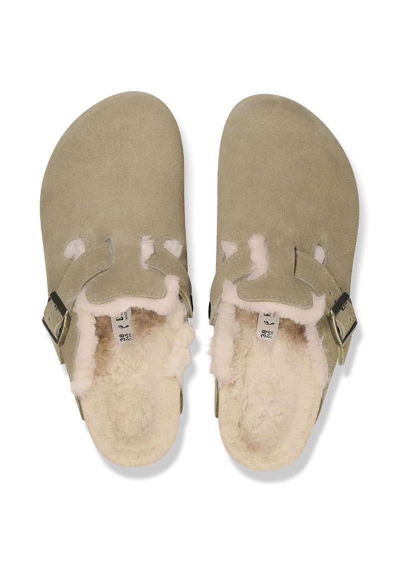 Sandales en daim à enfiler de couleur vert muted, avec une douce doublure en shearling crème. Comprend deux découpes et une boucle en métal réglable.