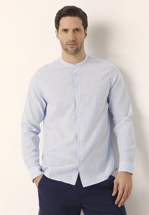 Camisa de manga larga a rayas de color azul claro con cuello de banda y cierre frontal completo de botones. Fabricada con una tela texturizada, presenta rayas verticales blancas.