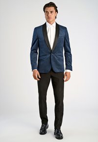 Mörkblå sammetsfrack med svart satinkrage, kombinerad med svarta byxor och blanka svarta skor, tillsammans med en vit skjorta.