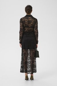 Mustmustel lace kleit, millel on lillemustrid, pikad varrukad ja läbipaistev seelik. Ühendatud tumeroheliste kontsakingade ja väikese musta käekotiga.