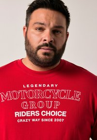 Camiseta de algodón roja con texto blanco en negrita: "GRUPO LEGENDARIO DE MOTOCICLETAS ELECCIÓN DE LOS CONDUCTORES MANERA LOCAMENTE DESDE 2007." Textura suave, cuello redondo.